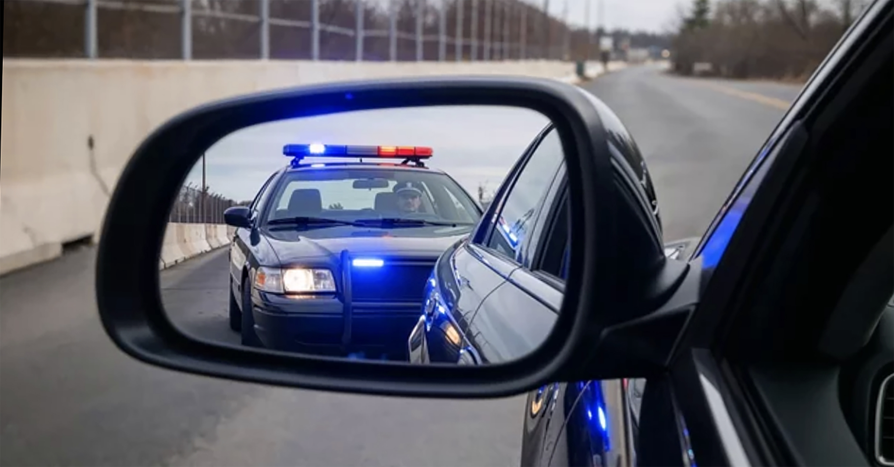 A police cruiser seen in the rearview mirror of a car.